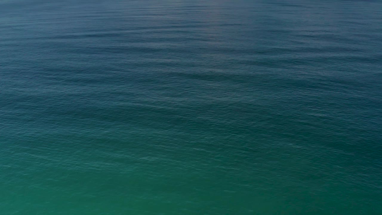 Rippled Los Cabos ocean water shows a stronger aquamarine area beneath darker blue water, with no visible people.