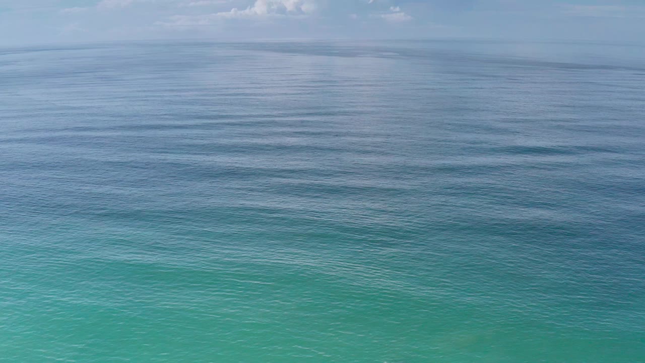 Wide turquoise ocean water under a pale blue sky.