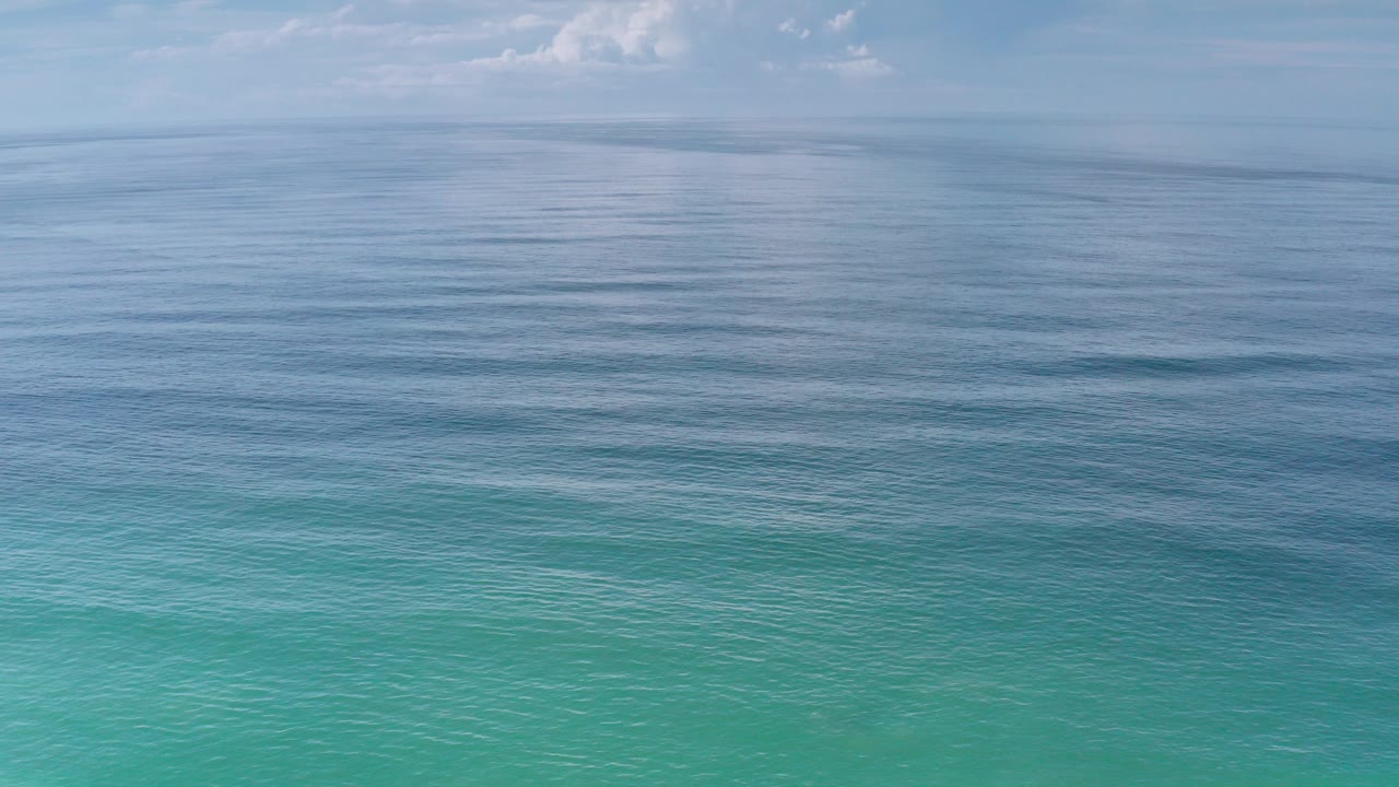Calm blue ocean beneath a cloudy sky