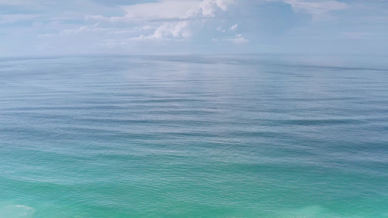 Second frame shows the Los Cabos water surface filling the lower half, darker blue ocean bands near the horizon, scattered clouds overhead, and no visible people.