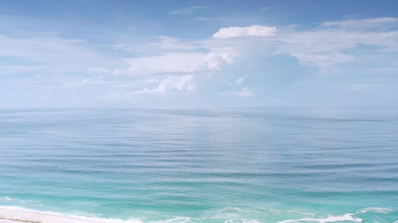 Los Cabos ocean view one second in, with the horizon held low, soft cloud shapes above, faint surface ripples, and no visible people.