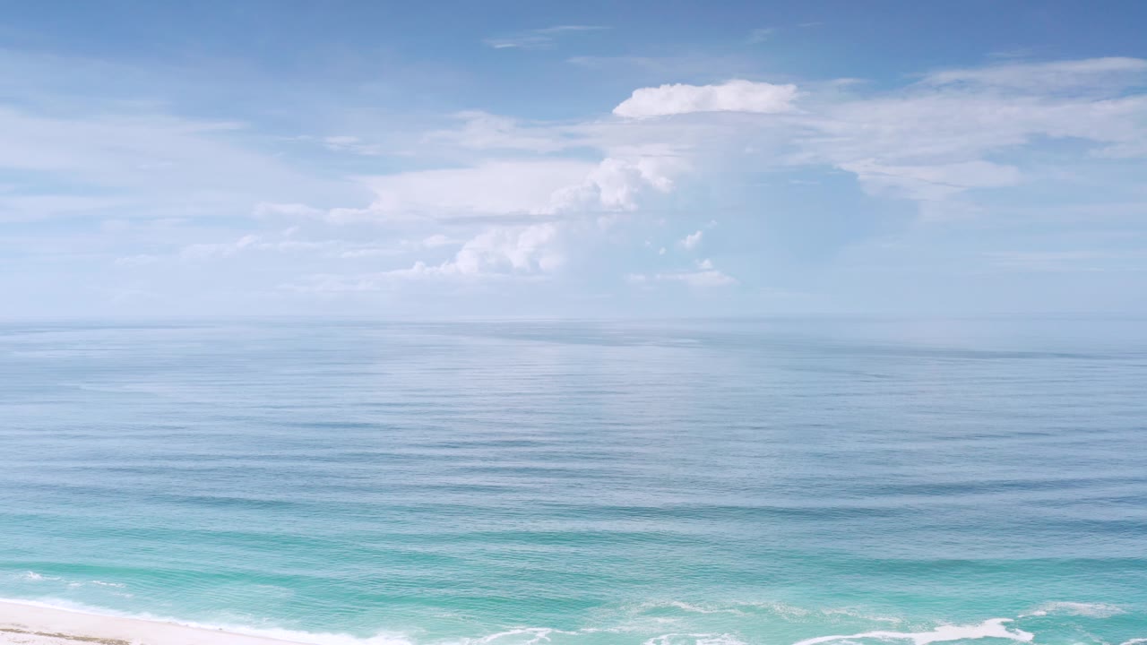 Two seconds into the Los Cabos shot, the frame shows open water, a pale cloud bank, bright turquoise shallows near the bottom, and no visible people.