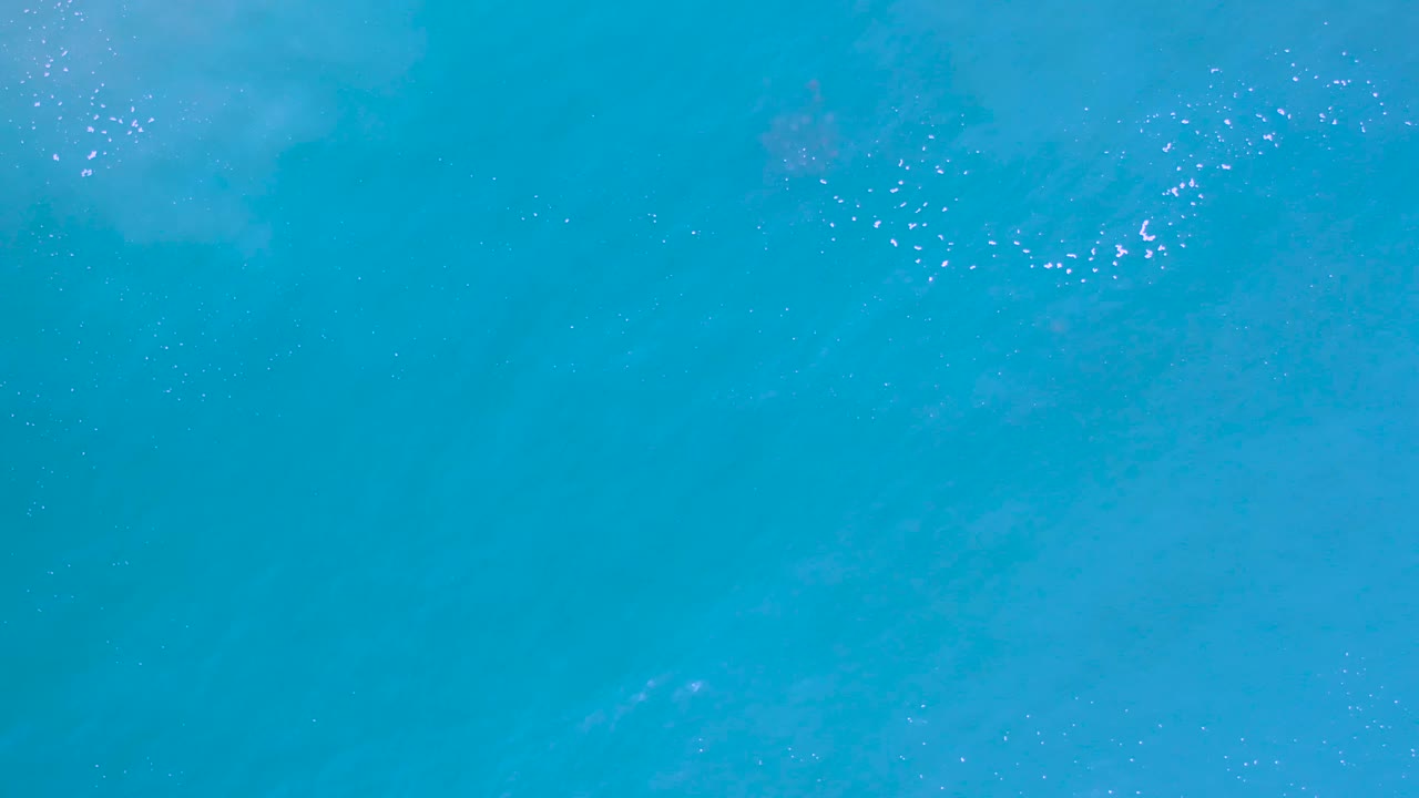 Turquoise ocean surface in Los Cabos with pale cloudy water patterns, minimal foam, and no visible people or vessels.