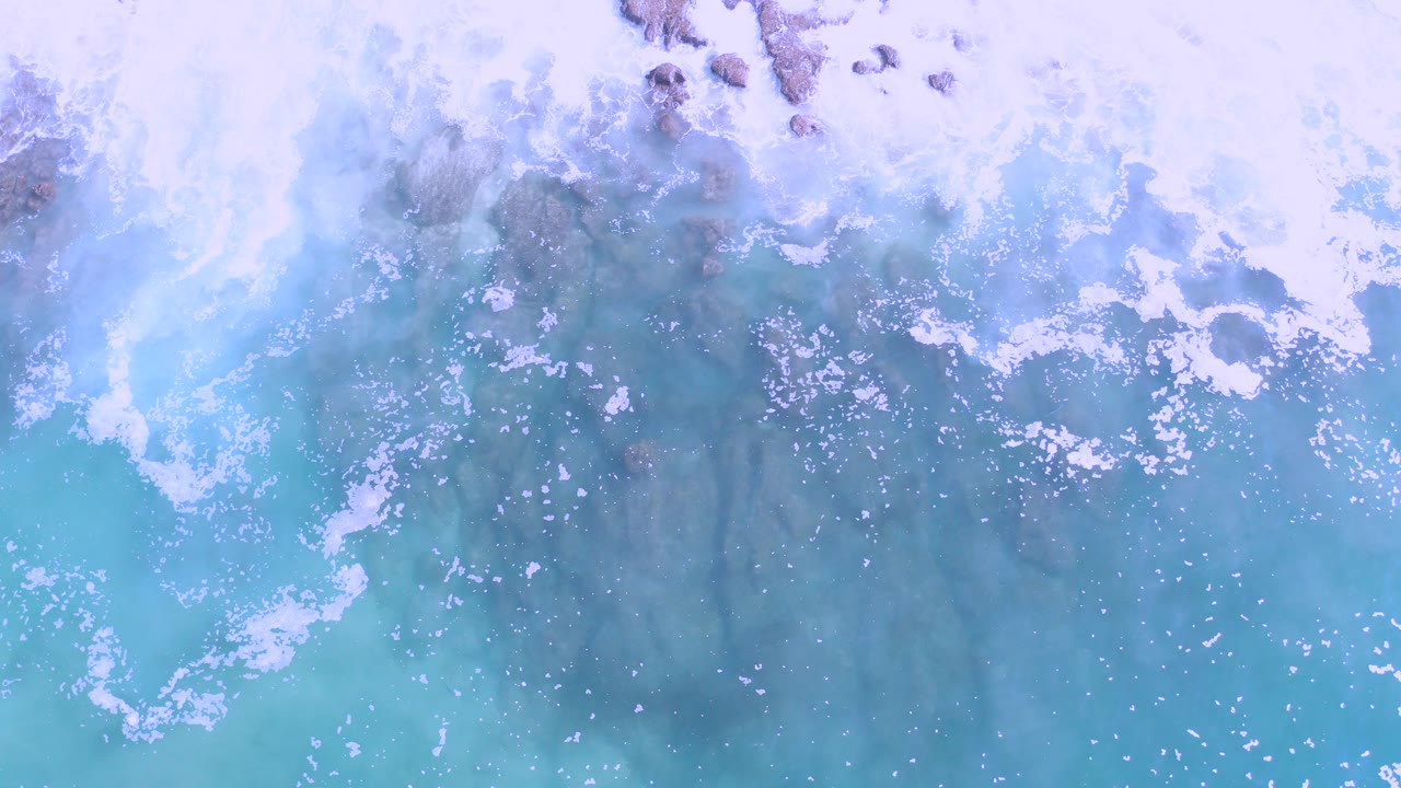Overhead turquoise sea with white foam patterns
