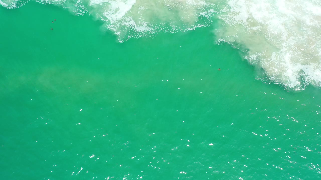 Turquoise ocean water with white surf foam along the top edge.