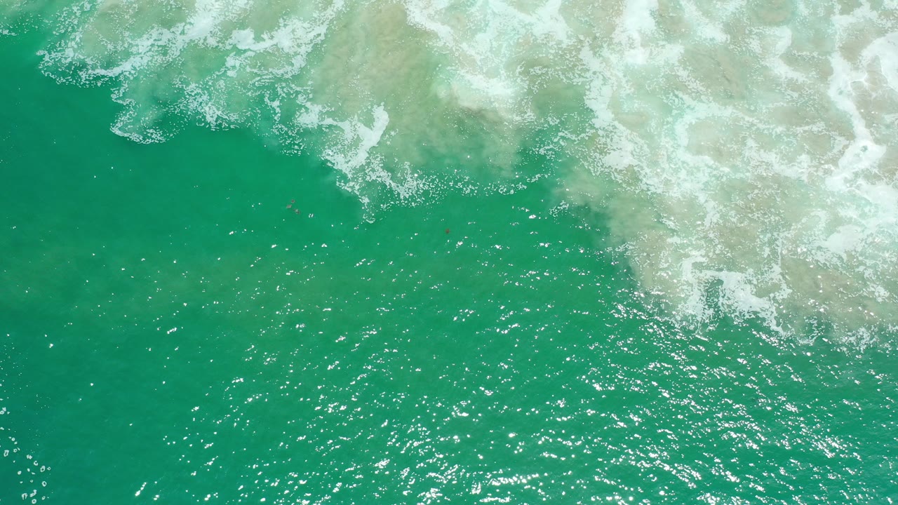 Overhead turquoise ocean water with white surf foam near the top.