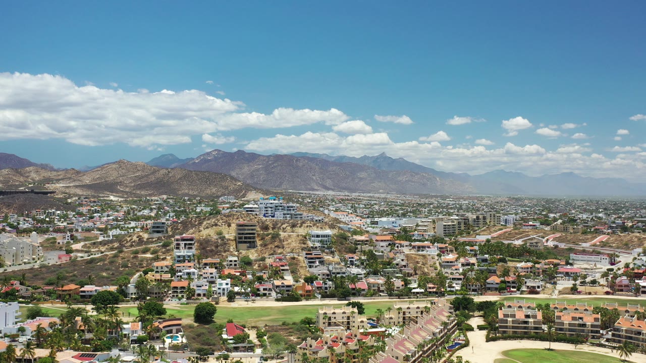 High aerial view across hillside buildings and a distant mountain range.