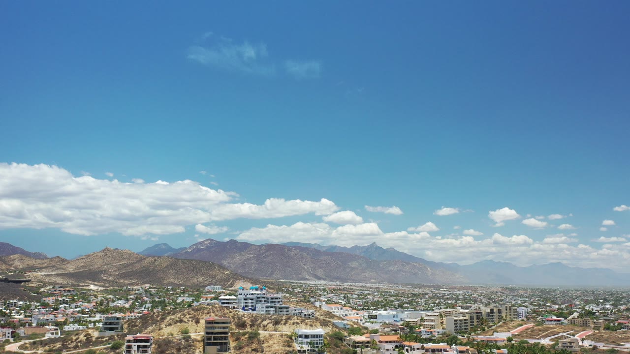 Wide aerial view of a desert city below mountains and blue sky