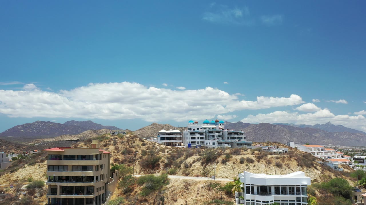 White hillside residences on desert slope under clouds