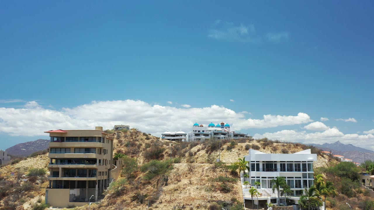 Wide hillside view with tall buildings, homes, dry slopes, blue sky, and no visible people.