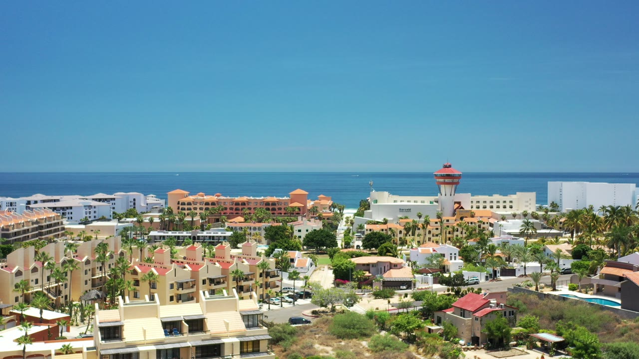 Aerial view of resort buildings and ocean under a clear blue sky.
