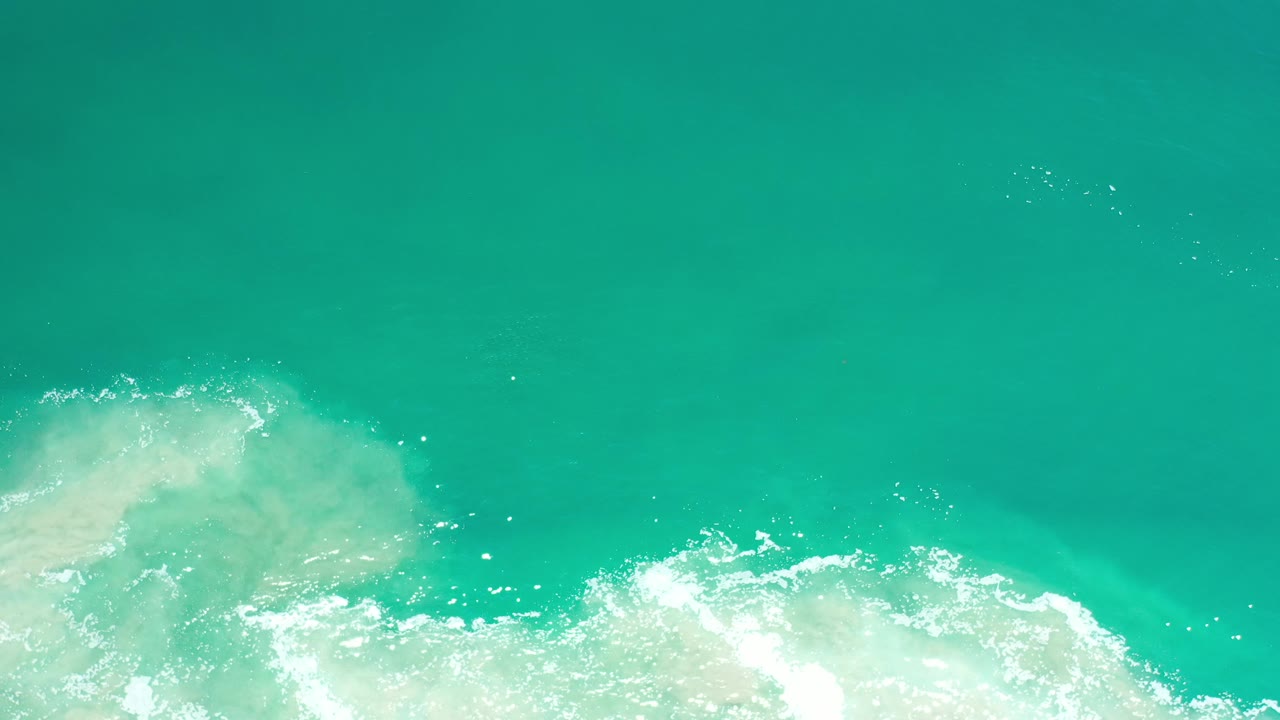 Turquoise-green water above a bright band of foamy surf.
