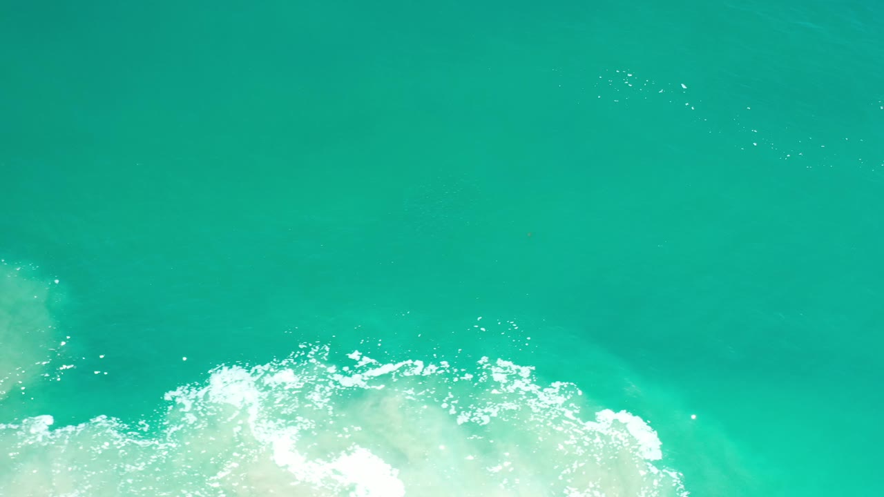 Turquoise sea with white foam pushed across the lower edge.