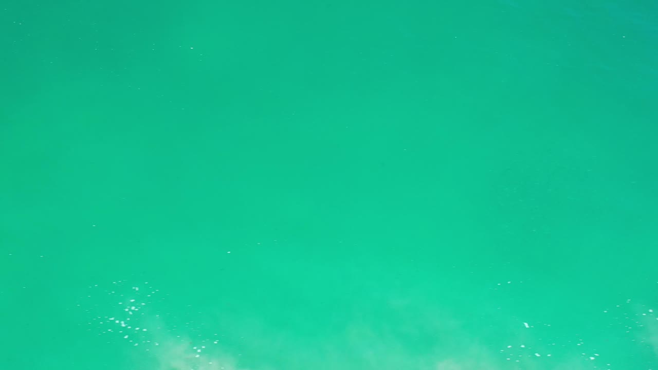 Open teal water with small bright reflections near the lower left.