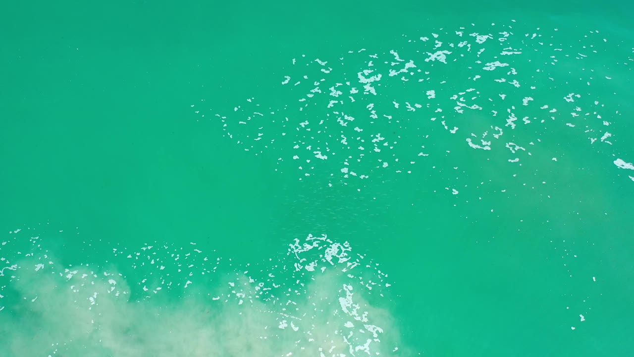 Turquoise sea surface with foam and bright glints