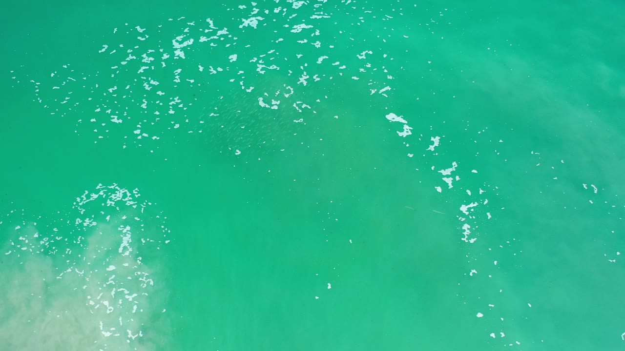 Overhead view of turquoise water off Los Cabos, Mexico, with white reflections near the upper left and no visible people.