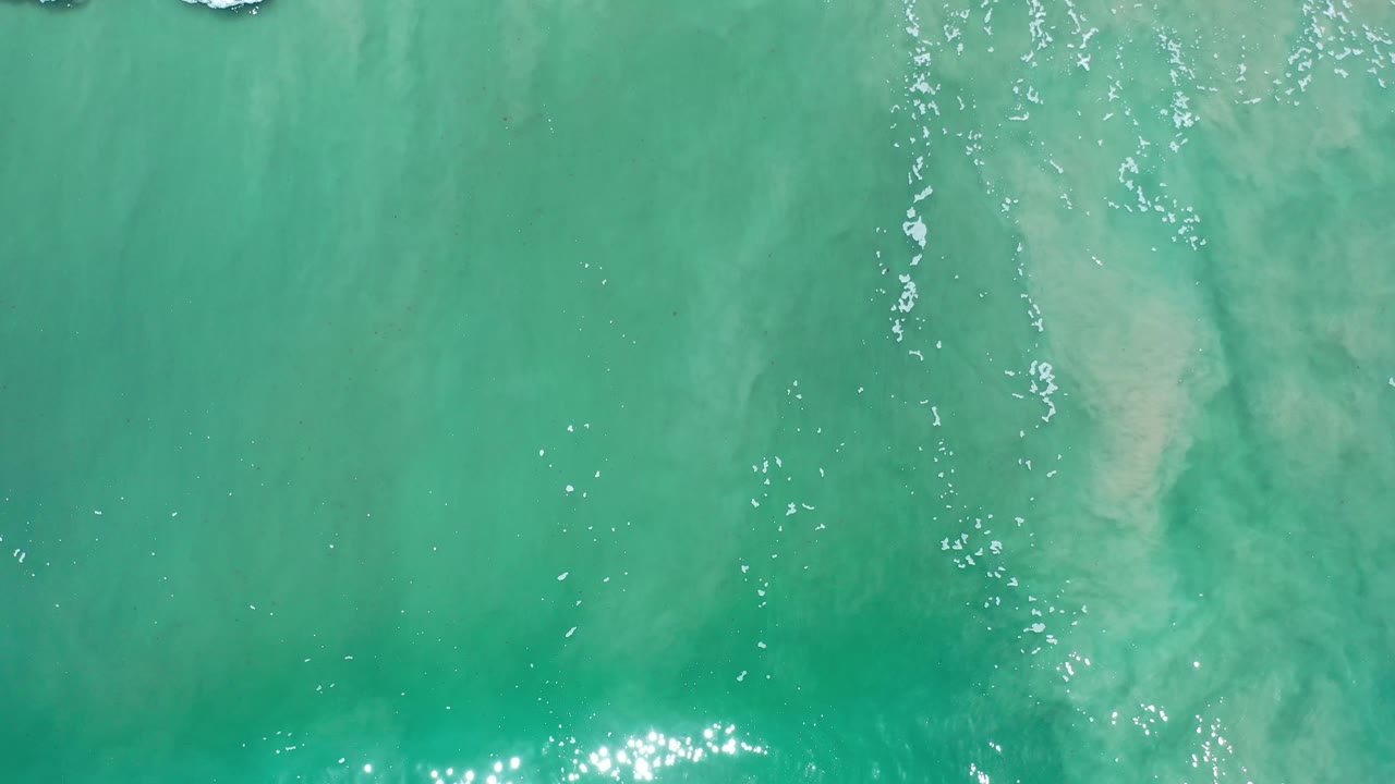 Overhead turquoise-green water with a bright sparkle cluster near the lower edge.