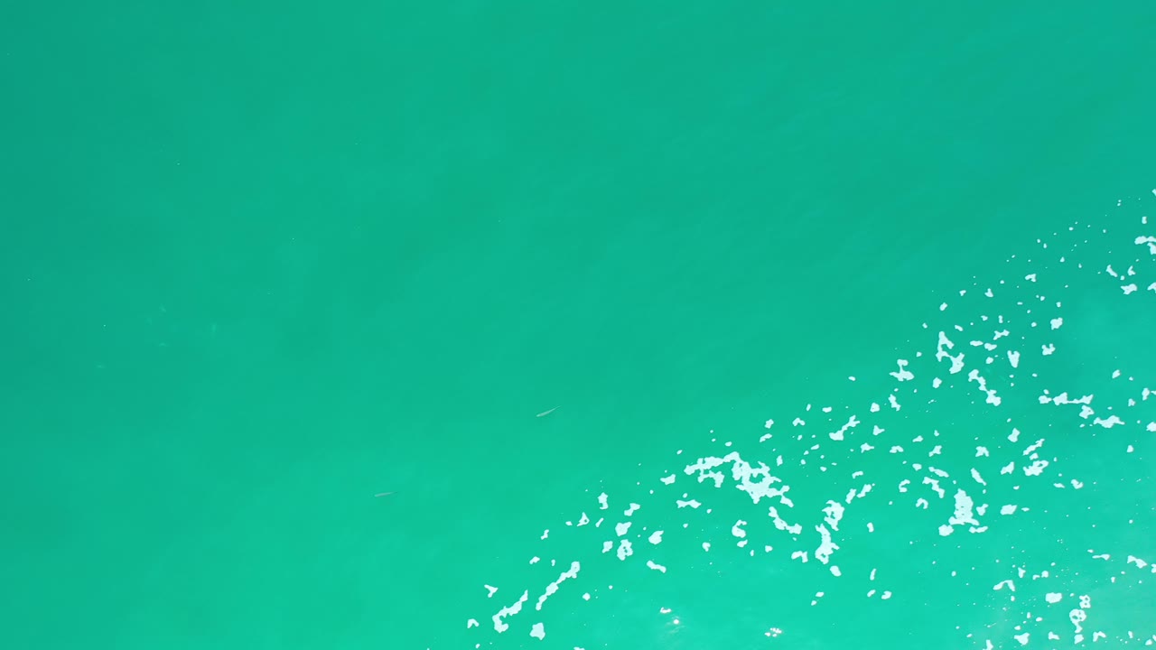 Aqua water surface with bright ripples along the right side.