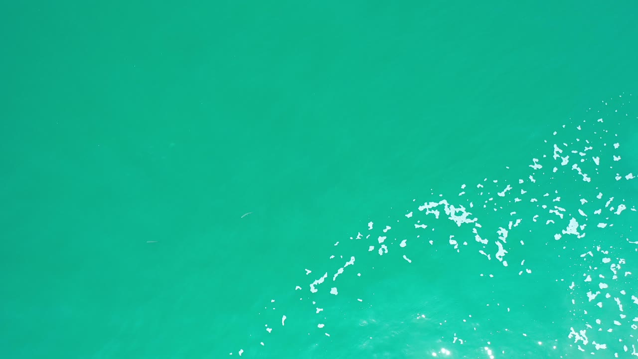 Turquoise seawater with bright surface sparkle near the lower edge.