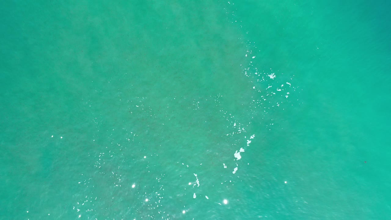 Turquoise ocean surface with small white foam marks