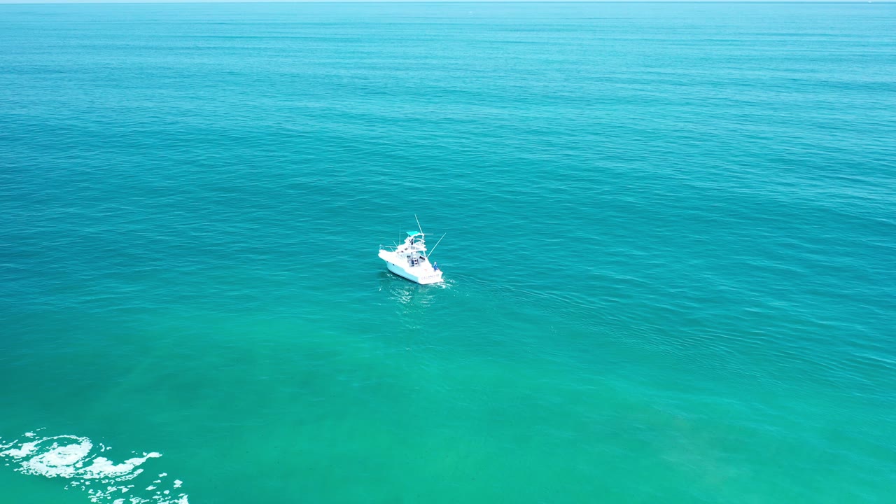 Small white boat on turquoise ocean water.