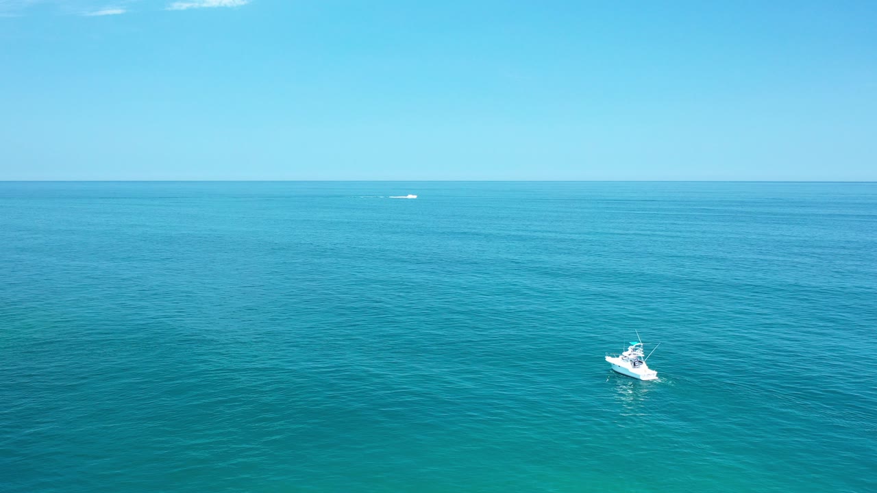 Small white fishing boat on wide blue-green ocean under a clear horizon.
