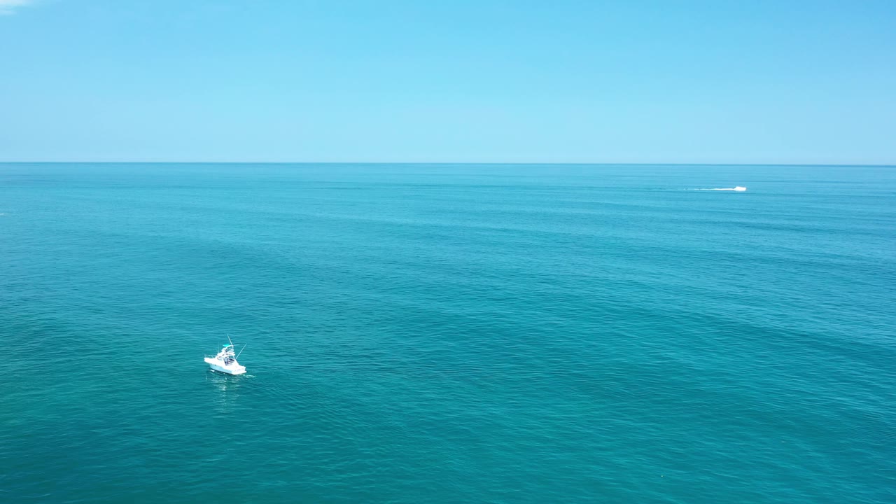 Small white boat on open turquoise water beneath a bright horizon.