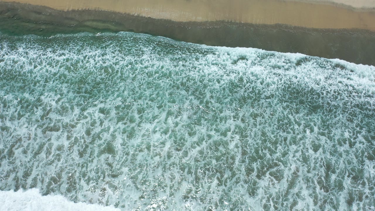 Overhead surf breaking onto wet sand