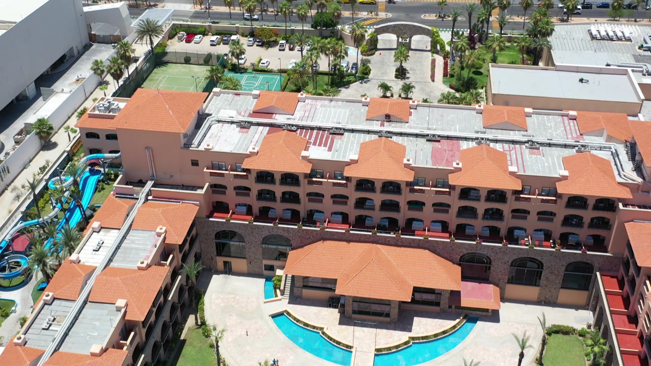 Aerial view of resort roofs, pool courtyard, tennis courts, and water slides.