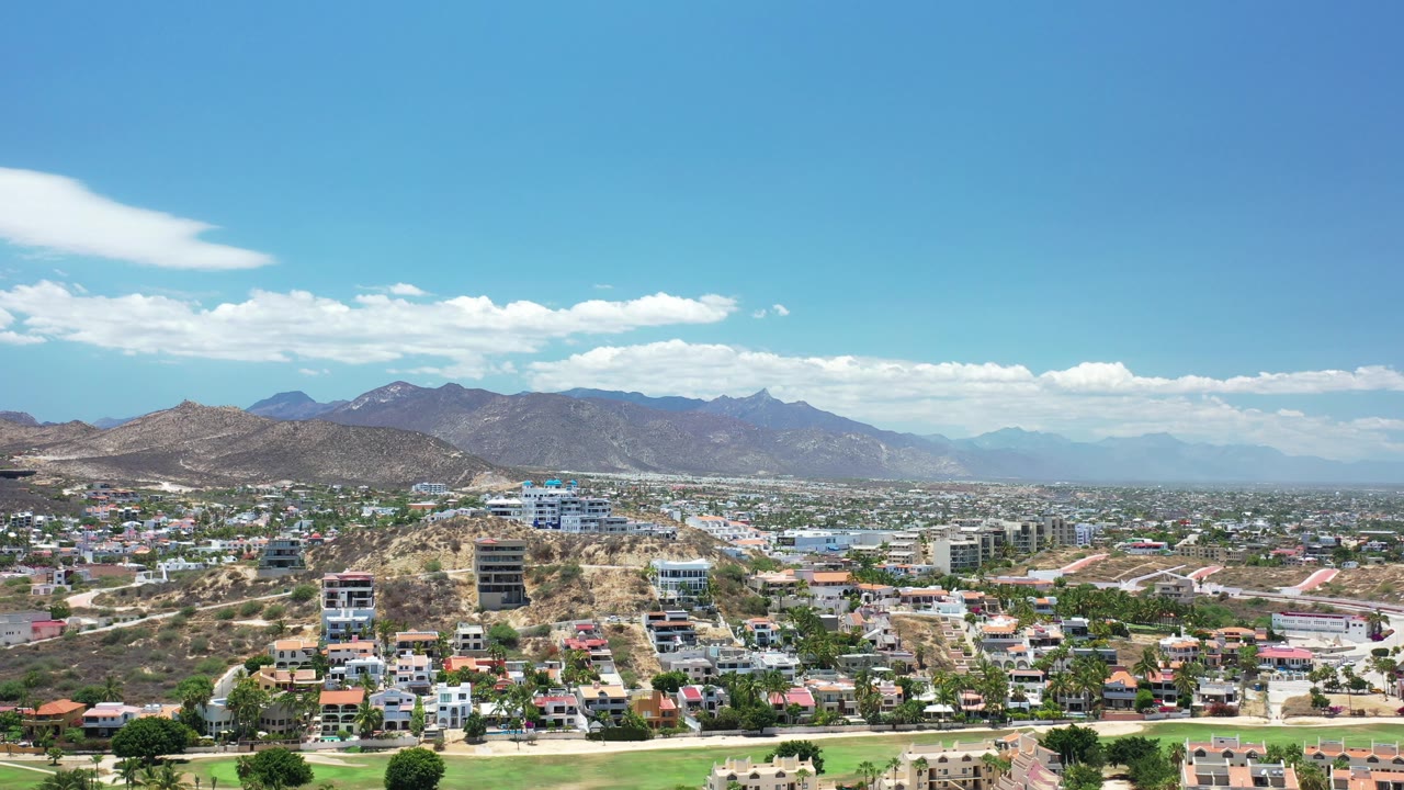 Wide view across Los Cabos rooftops toward rugged mountains.