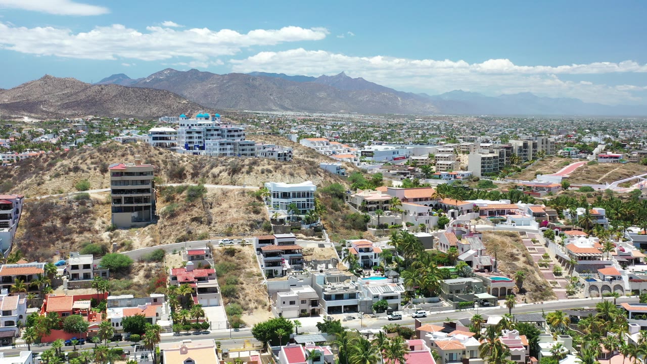 Aerial view of hillside homes and desert mountains under blue sky.