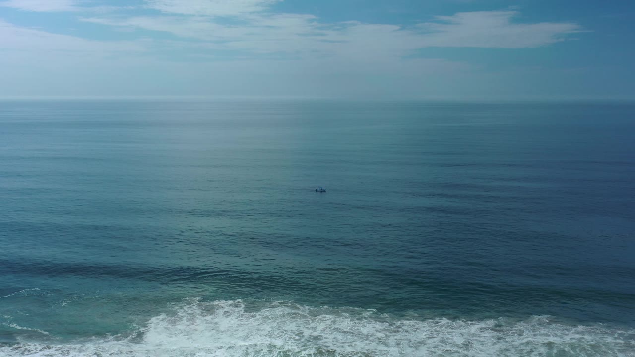 Open blue water, foamy surf, and a distant boat