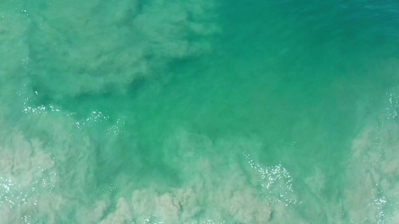 Aerial view of turquoise water and soft white surf texture.