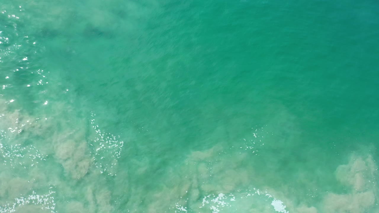 Shallow turquoise water with a vertical band of sparkle and foam