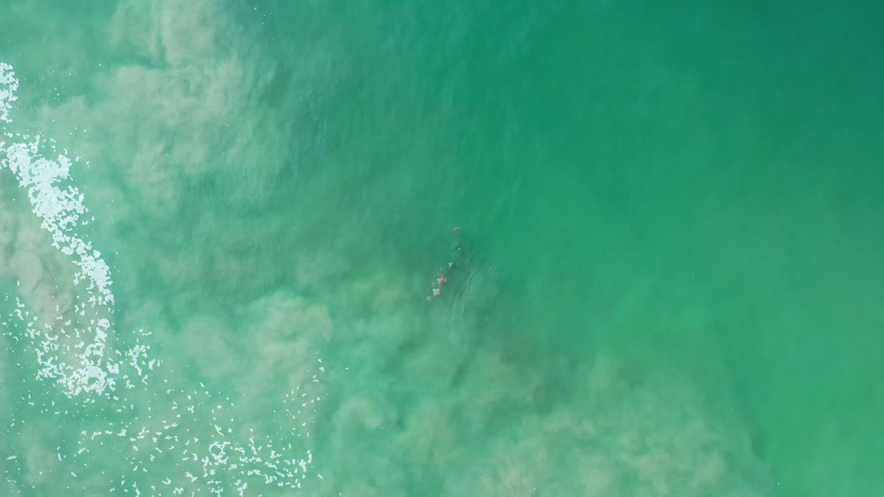 Turquoise ocean water with pale foam and sun glints.