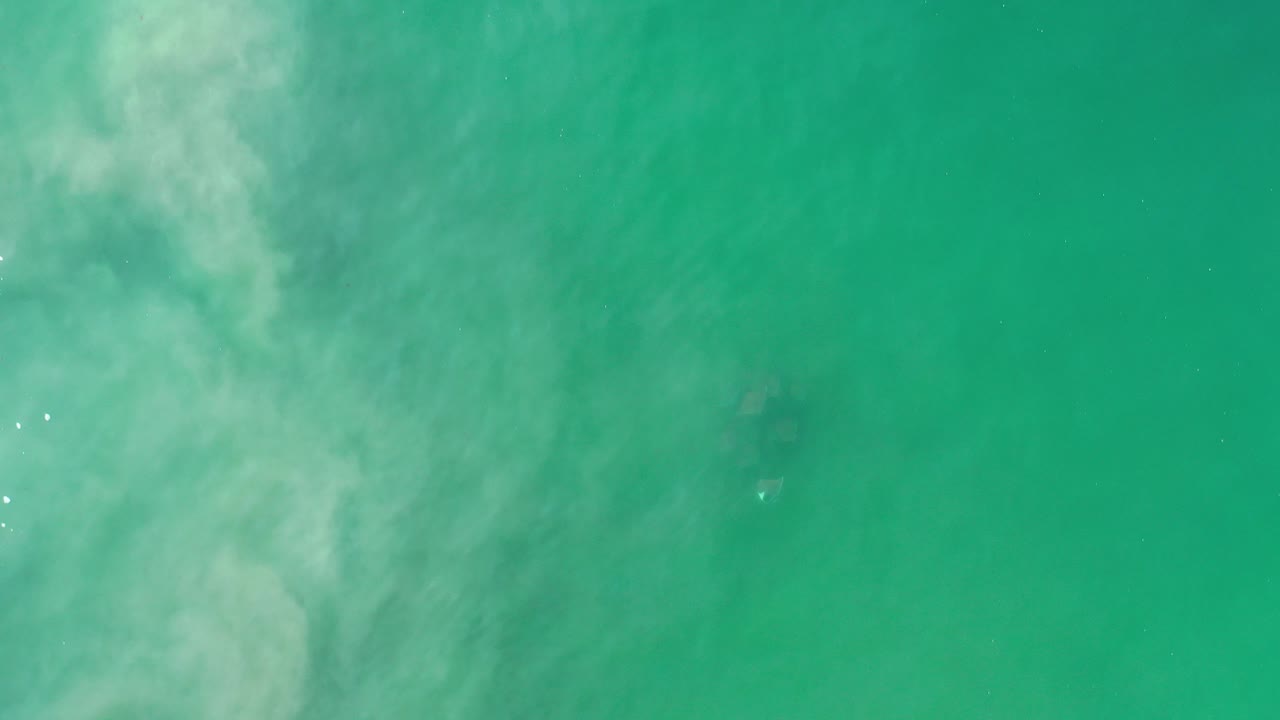 Opening frame of green water seen from above in Los Cabos, Mexico, with pale cloudy swirls and no visible people.