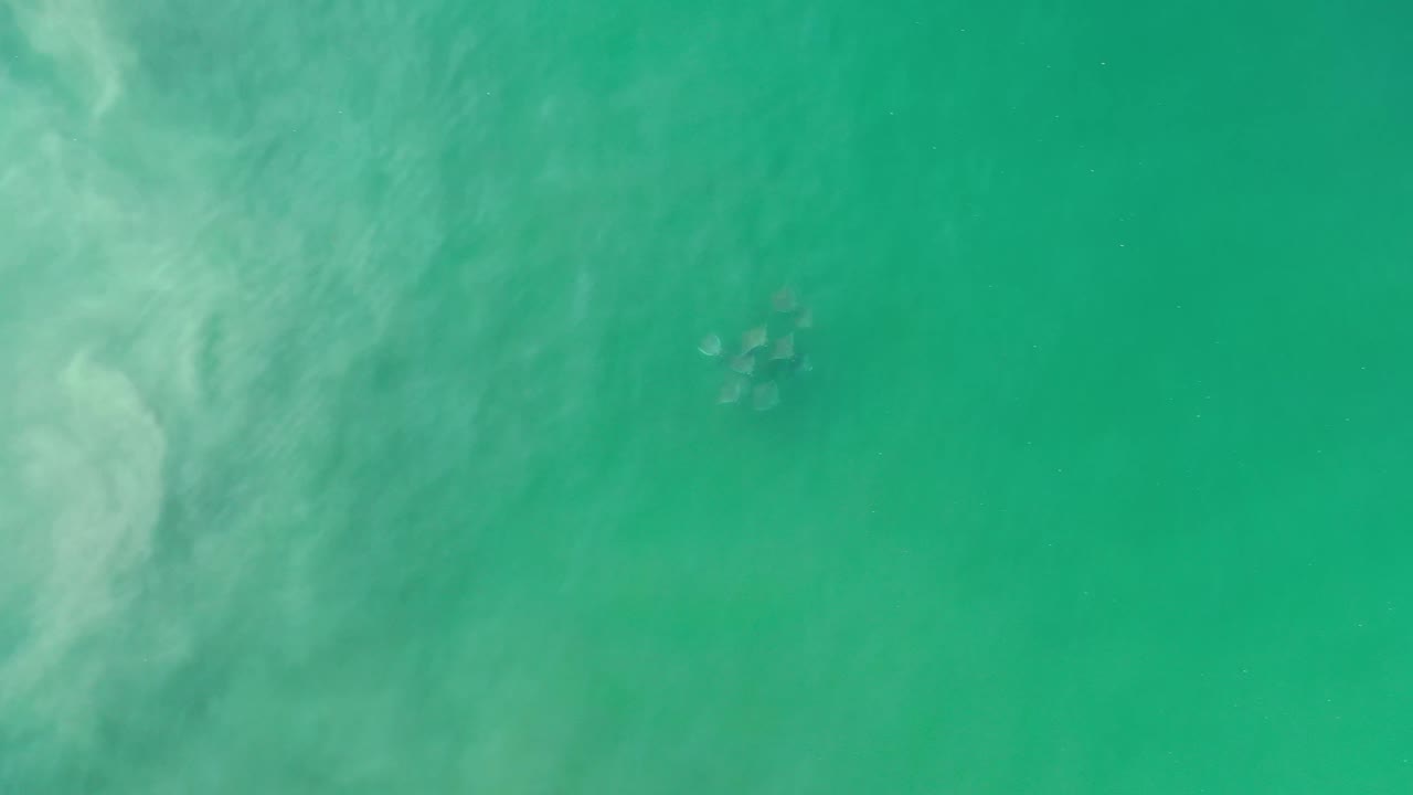 Aerial Los Cabos water frame with a faint cluster of light shapes near the upper center and no visible people.