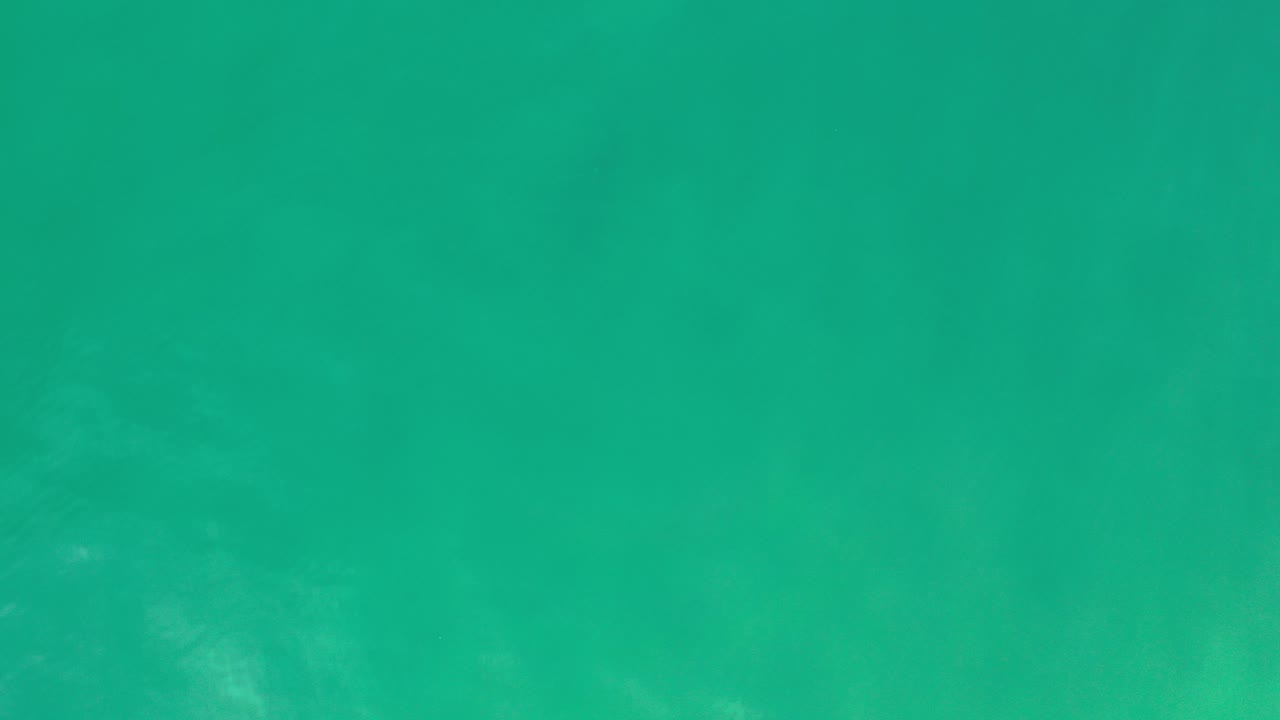 Green sea water fills the first frame from Los Cabos, Mexico, with faint darker patches under the surface and no visible people.