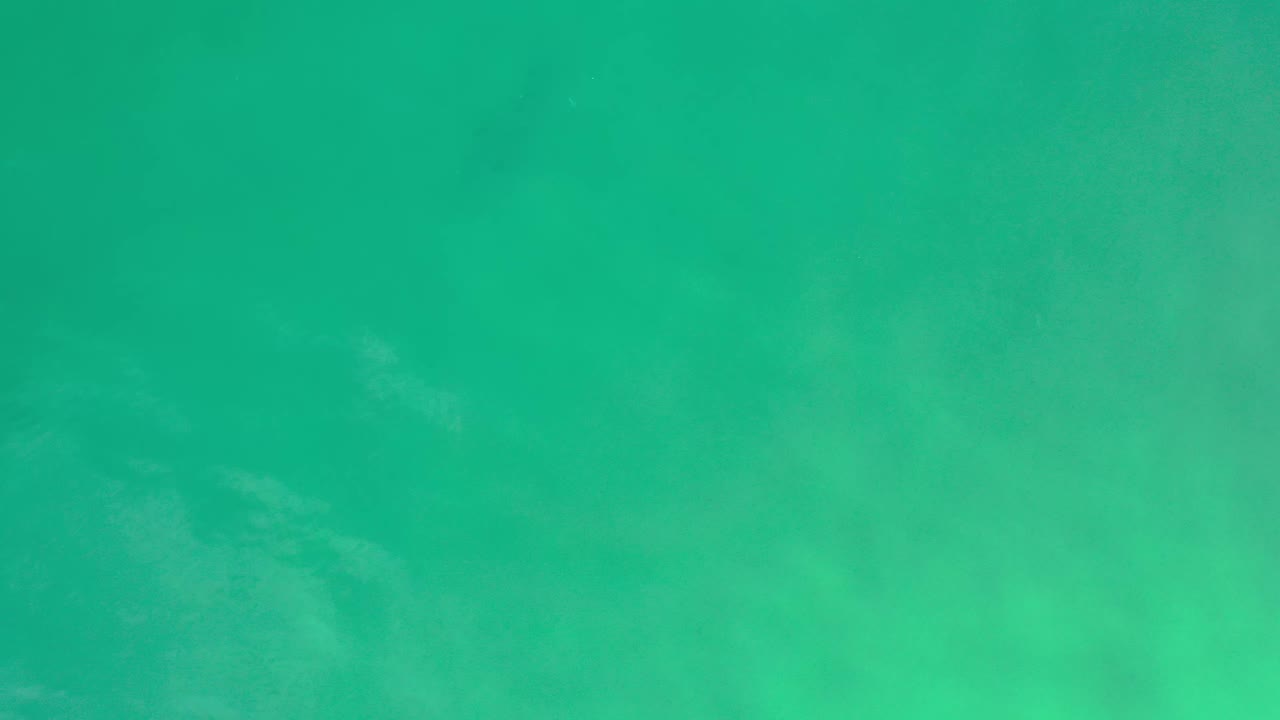 Overhead blue-green ocean surface in Los Cabos, Mexico, with a slightly darker upper band and no visible people.