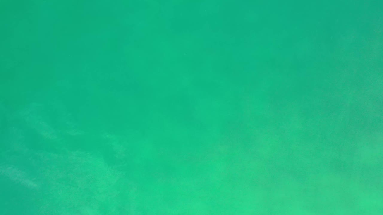 A slightly varied turquoise water surface appears in Los Cabos, with diffuse light patches and no visible people.