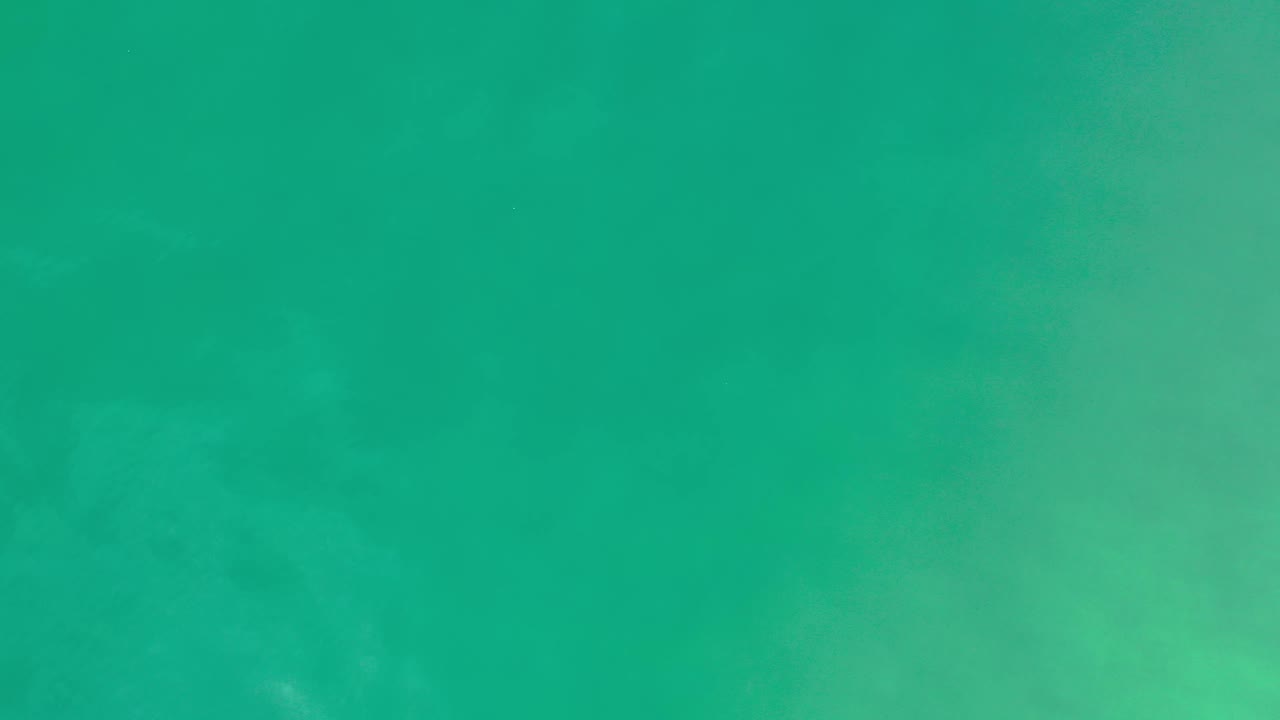 Aerial view of green coastal water in Los Cabos, Mexico with a broad smooth band across the center and no visible people.
