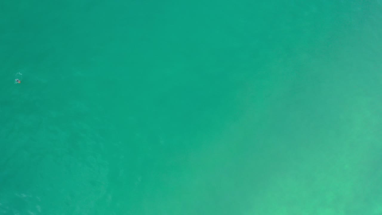 Top-down turquoise ocean surface with faint pale patches