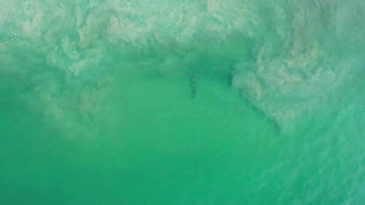 Pale sand haze across the upper part of teal water.