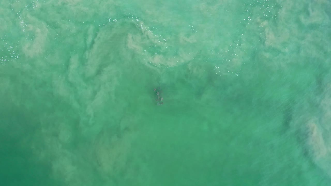 Turquoise green water with pale suspended patterns and bright glints.