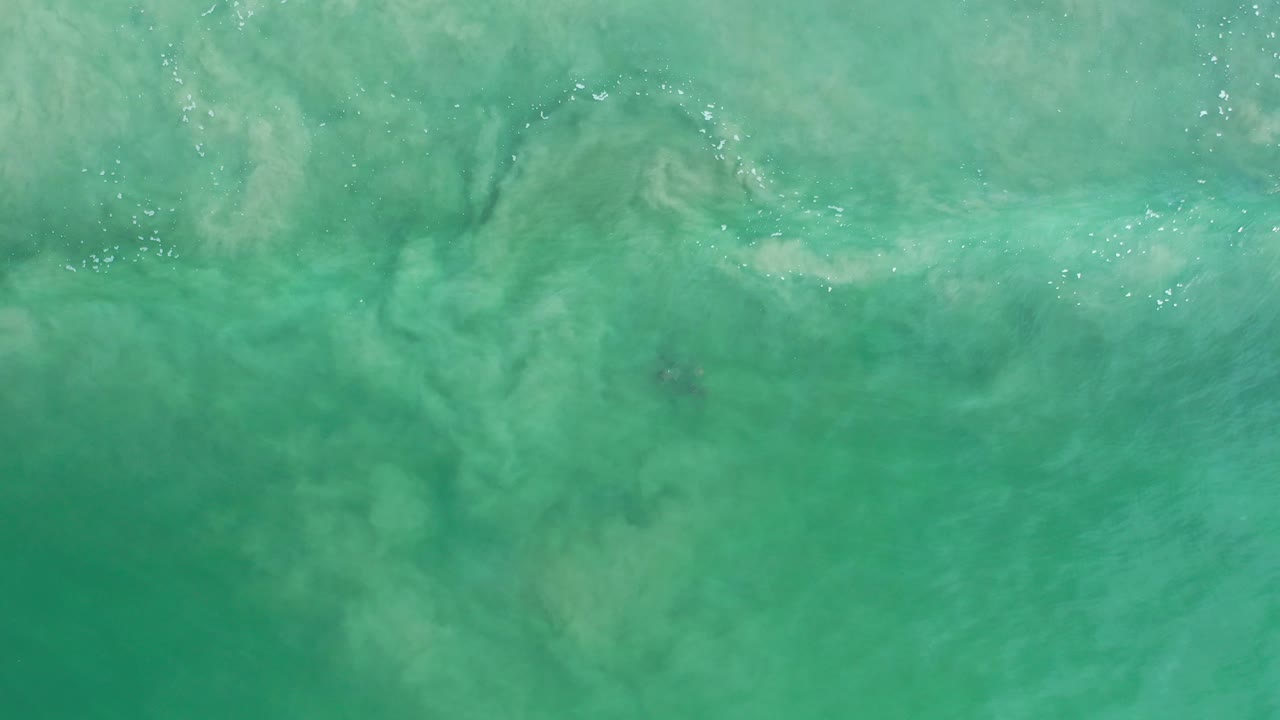 Turquoise water with scattered white sparkle and submerged sand swirls.