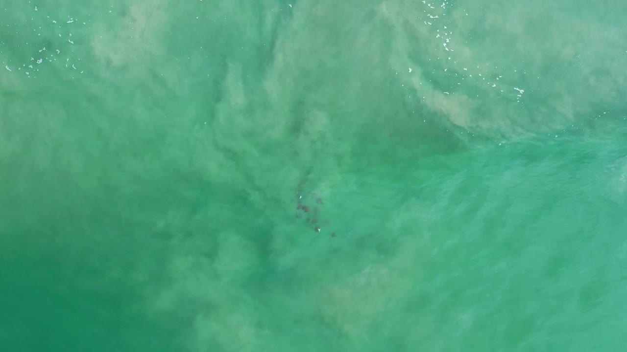 Overhead Los Cabos seawater frame with pale cloudy wave patterns spread across the green surface and no visible people.