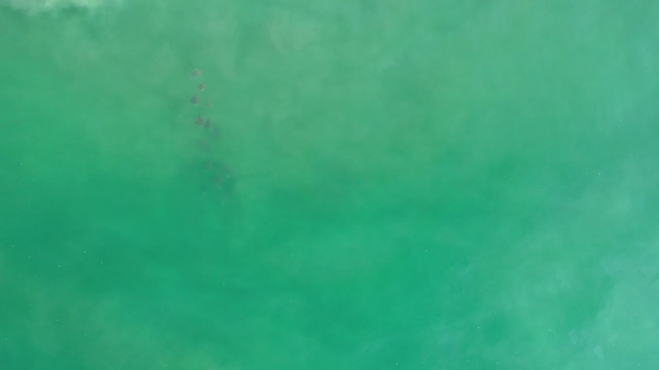 Turquoise ocean water with cloudy lighter areas under the surface.