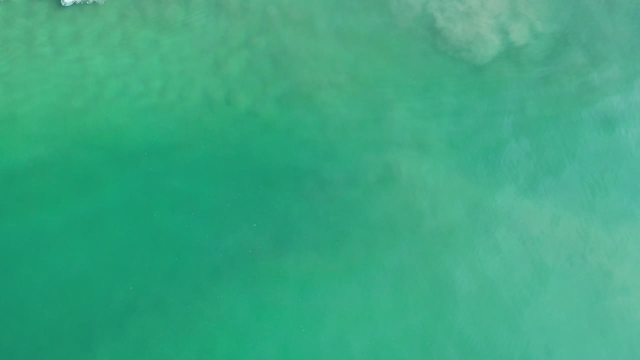 Clear green ocean water with soft cloudy patterns below the surface.