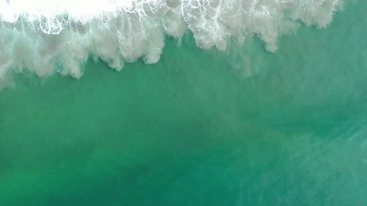 Breaking surf across the top of clear green water