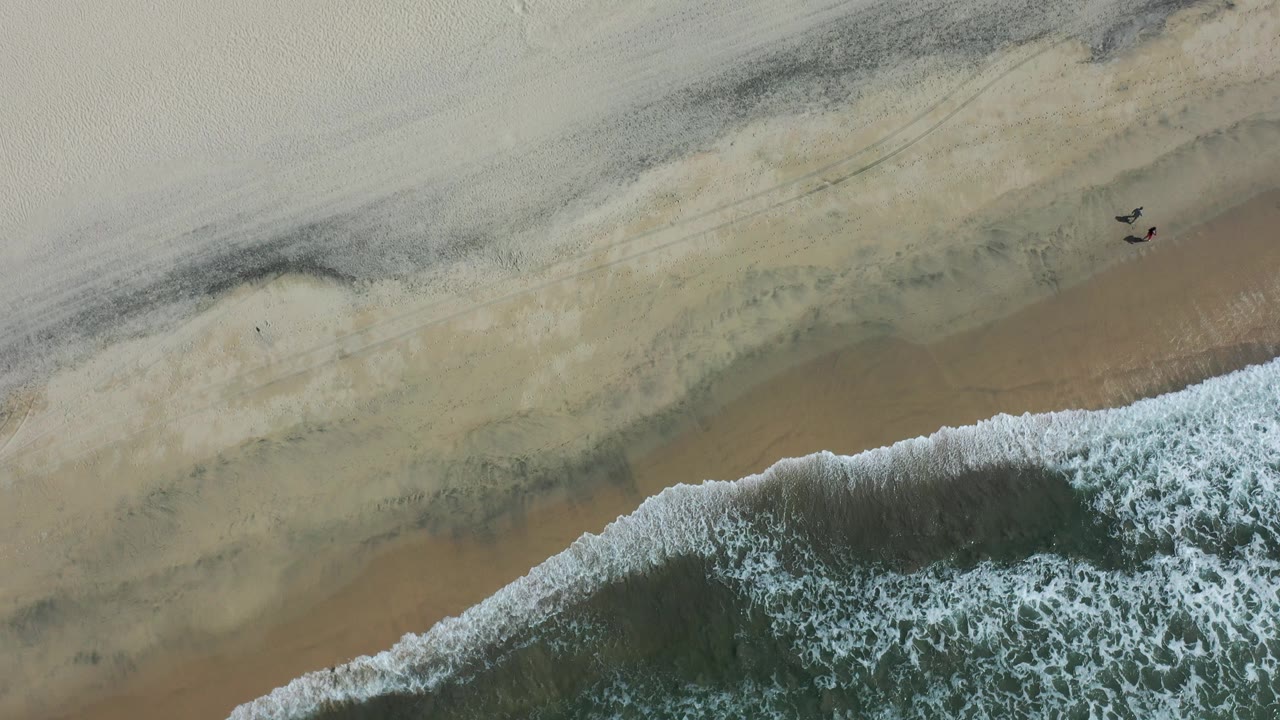 Overhead surf line washing onto pale sand.